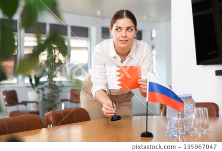 Young woman puts flags of Bahrain and Russia on table Young woman puts flags of Bahrain and Russia on table 135967047