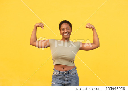Smiling fit young woman flexing muscles against 135967058