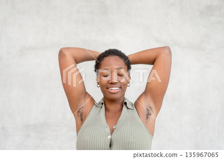 Smiling woman with raised arms showing underarm Smiling woman with raised arms showing underarm 135967065