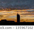 Silhouette of modern skyscraper against dramatic golden sunset sky 135967102