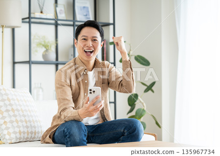 Middle-aged man using a smartphone in the living room Middle-aged man using a smartphone in the living room 135967734
