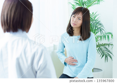 一名女子因腹痛在醫院接受治療,感覺身體不適 一名女子因腹痛在醫院接受治療,感覺身體不適 135967800
