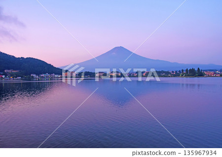 Early morning dawn on the shores of Lake Kawaguchi, with Mount Fuji dyed pale purple and a hazy upside-down image of Mount Fuji reflected in the ripples. Early morning dawn on the shores of Lake Kawaguchi, with Mount Fuji dyed pale purple and a hazy upside-down image of Mount Fuji reflected in the ripples. 135967934