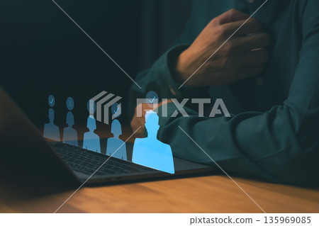 Businessman using laptop with virtual candidate profiles and check marks, symbolizing online recruitment, HR technology, digital hiring process, and employee selection in modern business management. Businessman using laptop with virtual candidate profiles and check marks, symbolizing online recruitment, HR technology, digital hiring process, and employee selection in modern business management. 135969085
