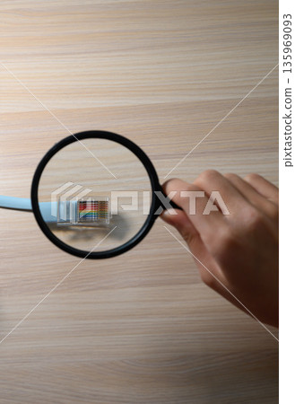 Inspecting a LAN cable with a magnifying glass Inspecting a LAN cable with a magnifying glass 135969093