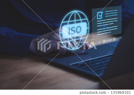 Person using laptop with ISO certification and digital checklist, symbolizing international quality standard, compliance management, business improvement, data security certification system. 135969101