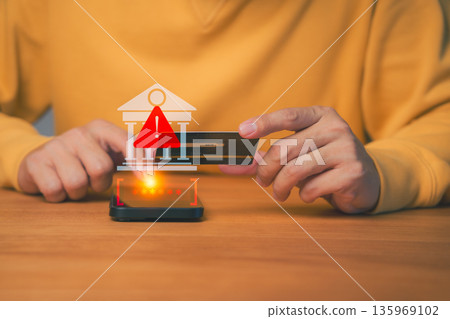 Person holding a credit card and smartphone with warning icon, symbolizing online banking fraud, security alert, or financial scam, cybersecurity, payment risk, or digital fraud prevention concepts. 135969102