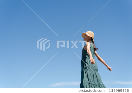 A young woman in a one-piece dress against the blue sky 135969556