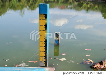 Water Level Gauge in a Polluted Pond with Natural Light Reflecting on the Surface for Environmental Monitoring 135969609