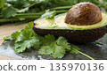 macro scene depicts a towering, textured brown avocado pit emerging from the creamy green valley of its flesh. In the background, oversized cilantro leaves resemble palm trees, 135970136
