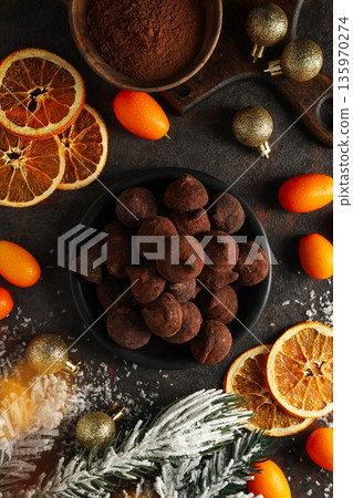 A dark surface displays chocolate, dried oranges, and gold A dark surface displays chocolate, dried oranges, and gold 135970274