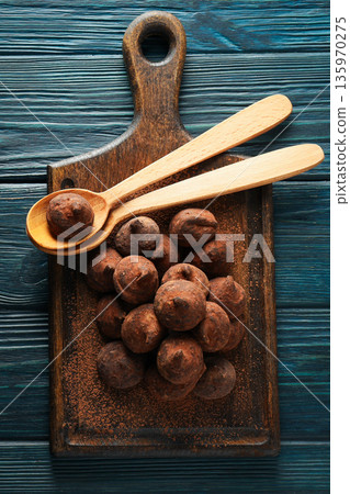 Cocoa balls rest on a wooden board beside two wooden spoons Cocoa balls rest on a wooden board beside two wooden spoons 135970275