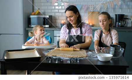 Mother with daughters roll and shape ginger cookie dough at the kitchen table, family bond and lifestyle concept Mother with daughters roll and shape ginger cookie dough at the kitchen table, family bond and lifestyle concept 135971614