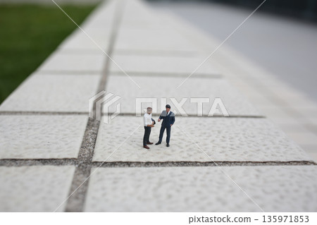 Miniature Business Figures Shaking Hands On Tiled Surface 135971853