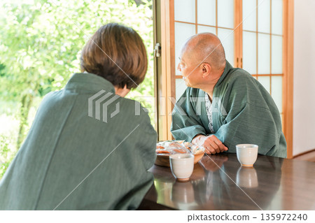 一對老年夫婦在溫泉之旅中放鬆身心,在日式房間喝茶。 一對老年夫婦在溫泉之旅中放鬆身心,在日式房間喝茶。 135972240