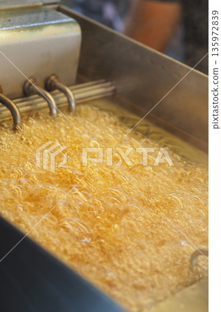 frying french fries in hot oil at a busy kitchen frying french fries in hot oil at a busy kitchen 135972839
