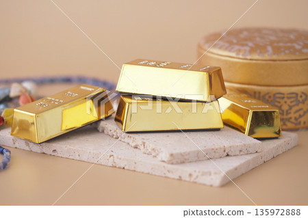 Gold bars shown with nearby decorative items Gold bars shown with nearby decorative items 135972888
