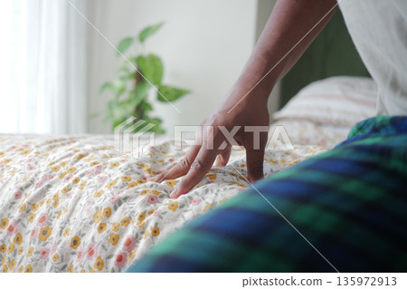 Person touching bed in a bright room during the morning Person touching bed in a bright room during the morning 135972913