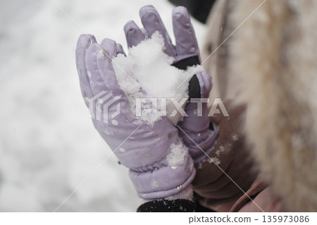 Child holds snow in hands on a winter day 135973086