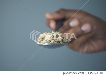 Spoon holding oats in hand ready for breakfast preparation 135973101