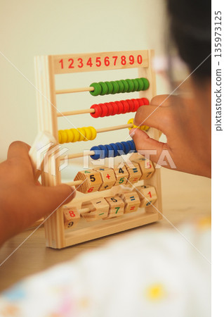 Child learns numbers with wooden abacus at home Child learns numbers with wooden abacus at home 135973125