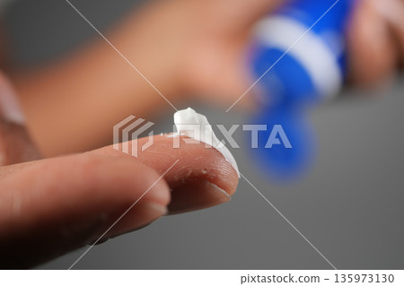 Applying cream to a finger during a skincare routine 135973130