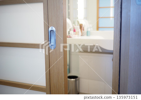 Wooden sliding door opens to a bright bathroom space Wooden sliding door opens to a bright bathroom space 135973151