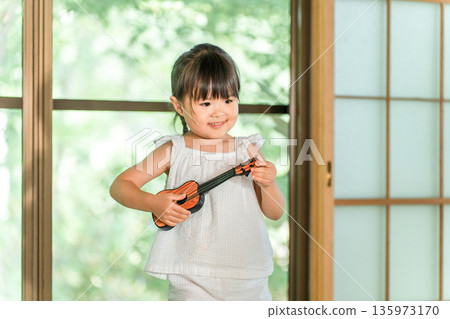 可愛的小女孩在玩烏克麗麗玩具 135973170