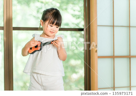 可愛的小女孩在玩烏克麗麗玩具 135973171