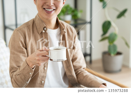 中間人在客廳裡喝咖啡 135973288