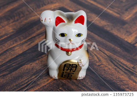 Maneki-neko on a wood grain background - Good luck and prosperity in business Maneki-neko on a wood grain background - Good luck and prosperity in business 135973725