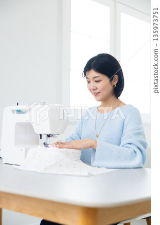 Woman sewing with a sewing machine 135973751