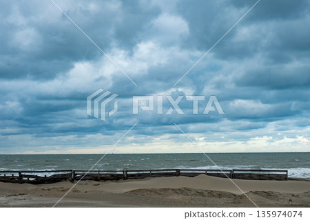 weathered logs on damp sandy coastlines, calm shoreline with aged timber beneath looming storm skies weathered logs on damp sandy coastlines, calm shoreline with aged timber beneath looming storm skies 135974074