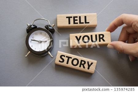 Tell your story symbol. Wooden blocks with words Tell your story. Businessman hand. Beautiful grey background with alarm clock. Business and Tell your story concept. Copy space. Tell your story symbol. Wooden blocks with words Tell your story. Businessman hand. Beautiful grey background with alarm clock. Business and Tell your story concept. Copy space. 135974285