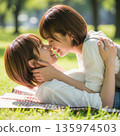 兩位年輕的日本女子躺在公園裡接吻 135974503