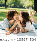 兩位年輕的日本女子躺在公園裡接吻 135974504