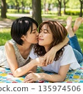 兩位年輕的日本女子躺在公園裡接吻 135974506