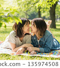 兩位年輕的日本女子躺在公園裡接吻 135974508