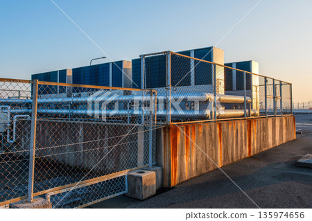 The building's air conditioning infrastructure and cooling system seen through the fence 135974656