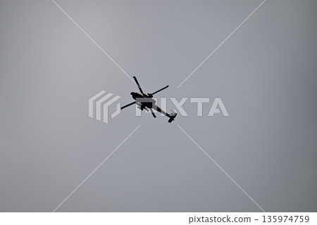 一架直升機的黑色輪廓在高高的雲層中飛行 135974759