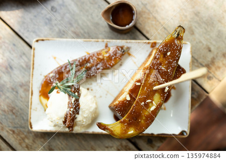 Bread toast with caramelized banana and ice cream on a wooden table. Bread toast with caramelized banana and ice cream on a wooden table. 135974884