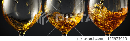 White wine of rich amber color being poured into a glass. 135975013