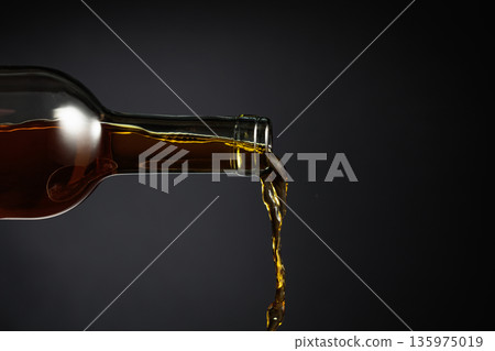 White wine of a rich amber color pours out of the bottle. White wine of a rich amber color pours out of the bottle. 135975019