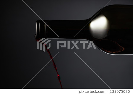 Red wine pours out of the bottle. Red wine pours out of the bottle. 135975020