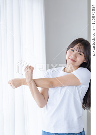 Young woman stretching by the window 135975084