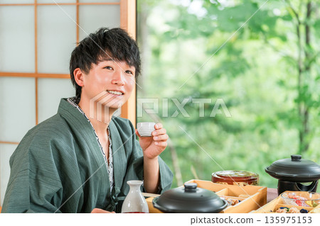 Young Asian man drinking sake with kaiseki cuisine at a ryokan (room dining, kaiseki cuisine, meal, luxury) 135975153