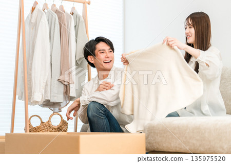 A young Asian couple tidying up their clothes in the living room at home, changing their clothes A young Asian couple tidying up their clothes in the living room at home, changing their clothes 135975520