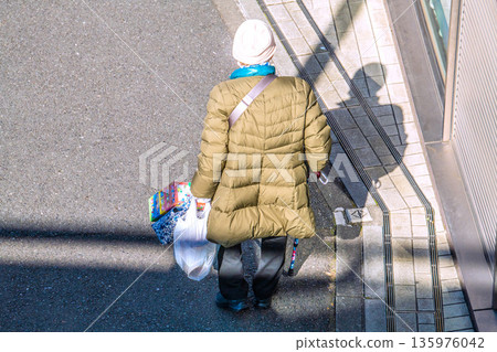 Yokohama cityscape in Japan: light and shadow... Aging society: An elderly woman with a cane (wearing a mask). On her way home from shopping, her left hand is gloved... Yokohama cityscape in Japan: light and shadow... Aging society: An elderly woman with a cane (wearing a mask). On her way home from shopping, her left hand is gloved... 135976042