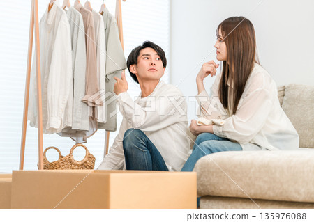 Couple organizing clothes in the living room at home, married couple (online shopping, dissatisfaction, regret, spending) 135976088