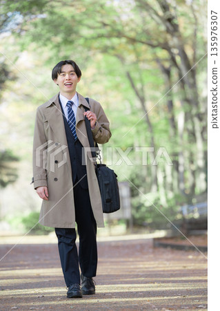 Smiling businessman on a job hunt or new graduate walking outside for sales with fresh greenery in the background 135976307